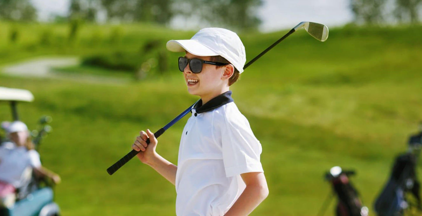 Young golfer wearing PROGEAR Golf Prescription Sunglasses on a sunny course, demonstrating unisex lifestyle fit and UV protection for all ages.
