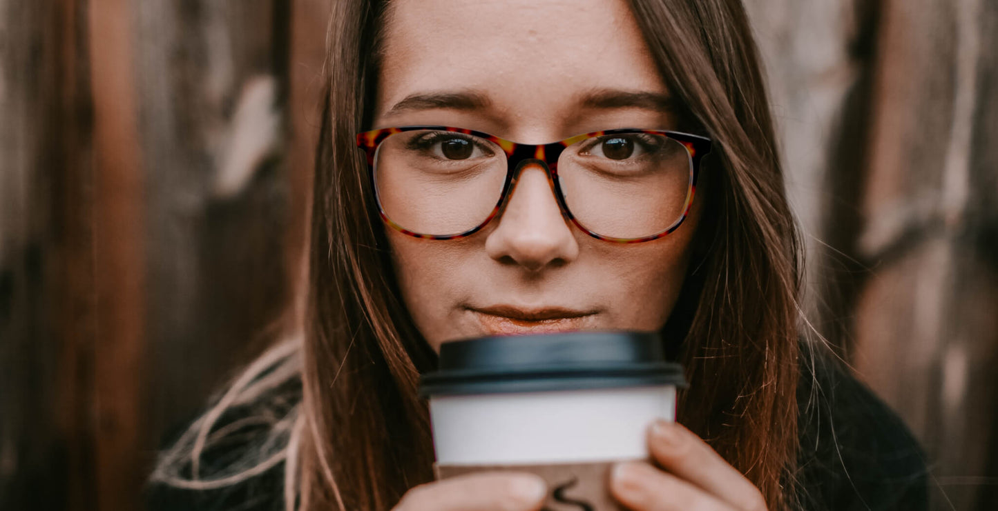 Woman wearing Free Form Eyewear™ Titanium 14g feather-light luxury German design glasses, tortoiseshell full frame, holding coffee cup.