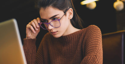 Woman wearing Free Form Eyewear™ Titanium 14g green full frame eyeglasses while working on a laptop. Lightweight luxury German design for men and women.