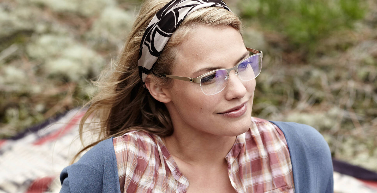 Free Form Eyewear™ Titanium 14g feather-light green half-frame glasses with blue light filter, worn by woman outdoors. Luxury German design for men and women.