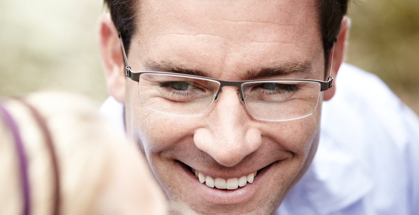 Free Form Eyewear™ Titanium 14g feather-light half frame glasses in green, worn by a smiling man. Luxury German design for men and women.